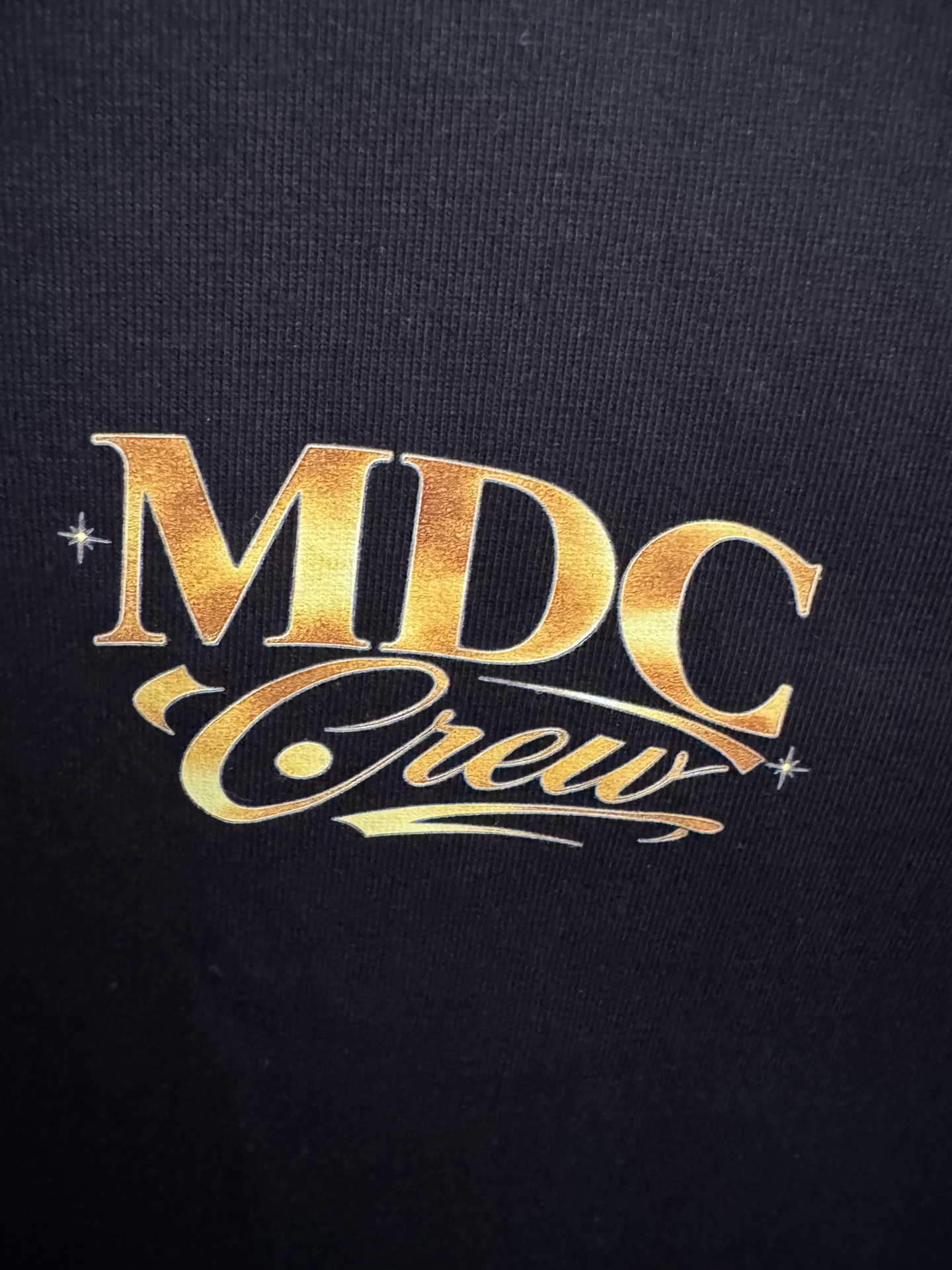 Close-up of the gold MDC Crew chest print